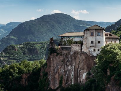 L‘Epifania Antico castello su scogliera con montagne boschive sullo sfondo