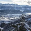 Transumanza in Alto Adige: un’importante tradizione Valle innevato con villaggio, montagne e lago sullo sfondo con cielo nuvoloso