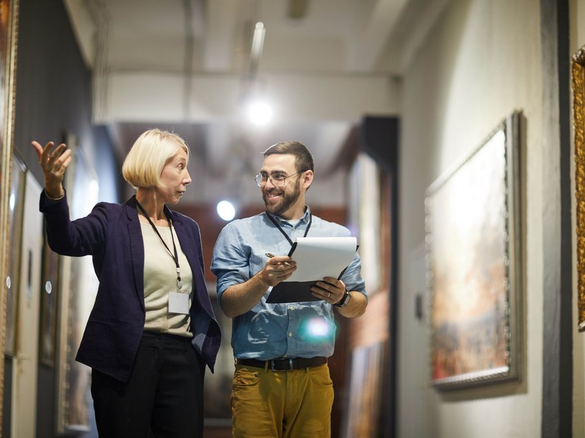 Geheimtipp Hotels in Südtirol 😎☀️ Zwei Museumsmitarbeiter diskutieren vor Gemälden im Kunstmuseum