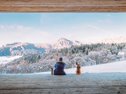 Transumanza in Alto Adige: un’importante tradizione Persona e cane seduti di fronte a paesaggio montano innevato in inverno