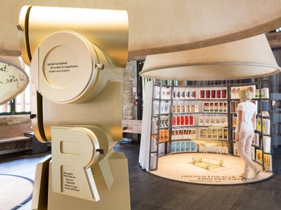 Il Museo della Frutticoltura a Lana Mostra con grande scultura dorata e donna davanti a parete di poster