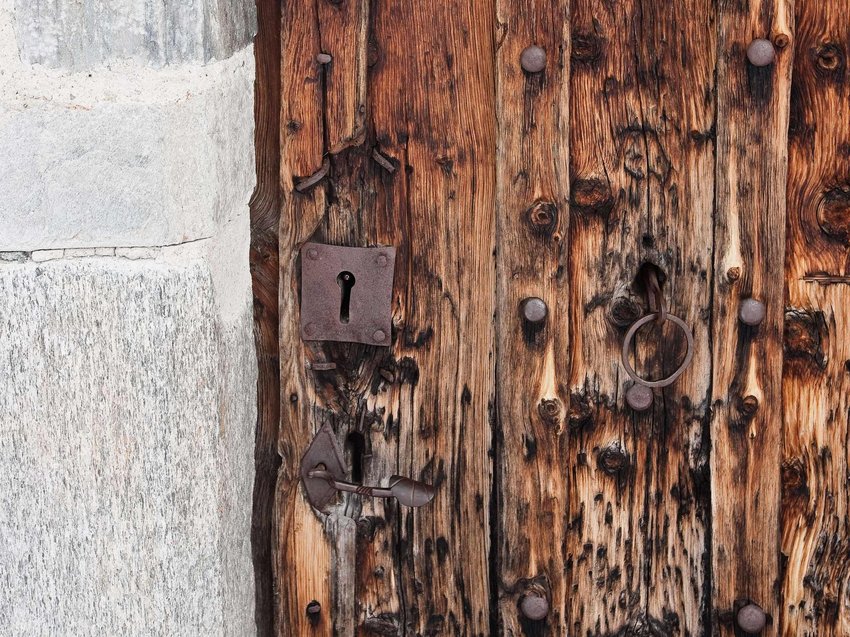Geheimtipp Hotels in Südtirol 😎☀️ Nahaufnahme einer alten hölzernen Tür mit rostigem Schloss und Türklopfer