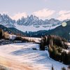 Transumanza in Alto Adige: un’importante tradizione Prato innevato davanti alle Dolomiti con case illuminate dal sole