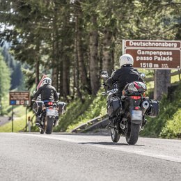Escursioni in Alto Adige: esperienze indimenticabili! Tre motociclisti attraversano il passo Gampen tra le montagne