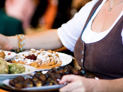 Transumanza in Alto Adige: un’importante tradizione Donna che porta piatti con varie pietanze tradizionali spolverate di zucchero a velo