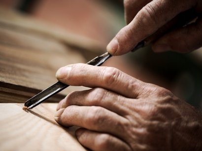 Transumanza in Alto Adige: un’importante tradizione Primo piano di mani che scolpiscono il legno con uno scalpello
