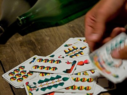 Transumanza in Alto Adige: un’importante tradizione Mano mescola carte da gioco italiane su tavolo di legno accanto a bottiglie