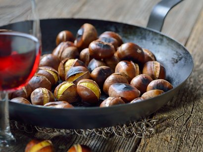 Transumanza in Alto Adige: un’importante tradizione Castagne arrostite in una padella con un bicchiere di vino rosso in primo piano