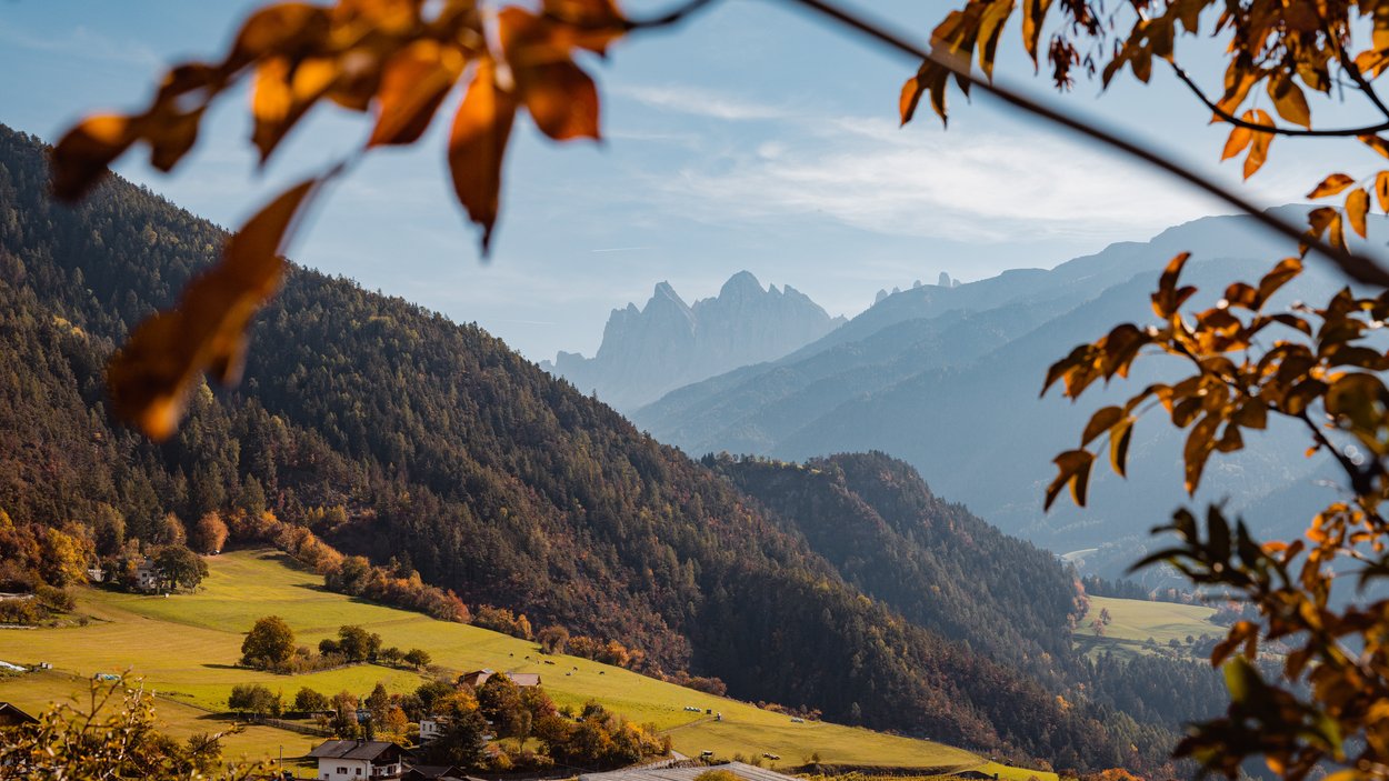 Die Entstehung eines altbekannten Brauches Herbstliche Berglandschaft mit grünen Wiesen und Häusern im Tal